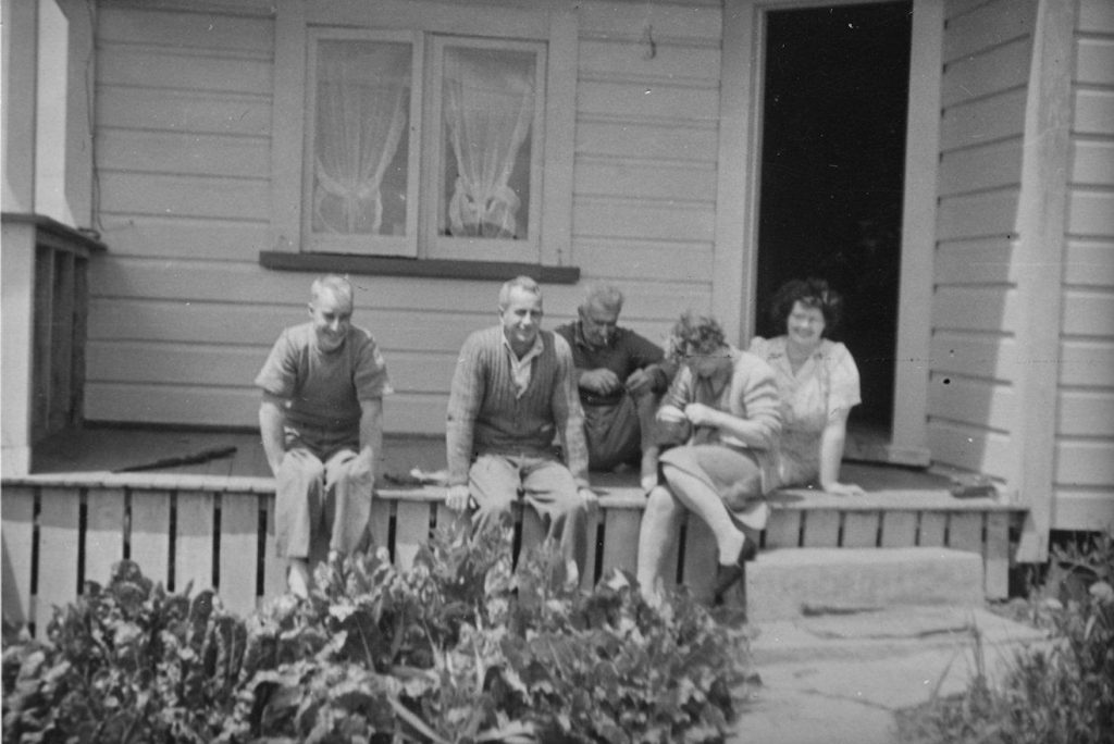 Group of 5 adults on verandah of house